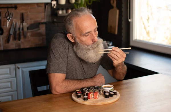 Бородатый Пожилой Человек Ест Суши Дома — стоковое фото