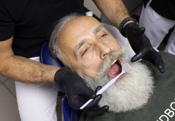 Bearded Senior man having dental treatment at dentist\'s office.