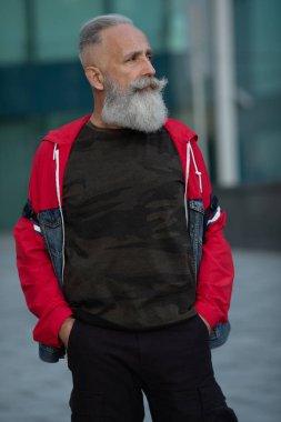 Bir şehirde yürüyen olgun sakallı aktif bir adamın portresi.