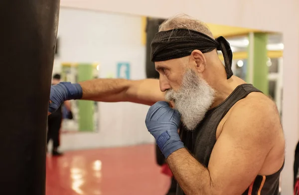 Senior male boxer ready to fight. Senior boxer in gloves boxing in gym