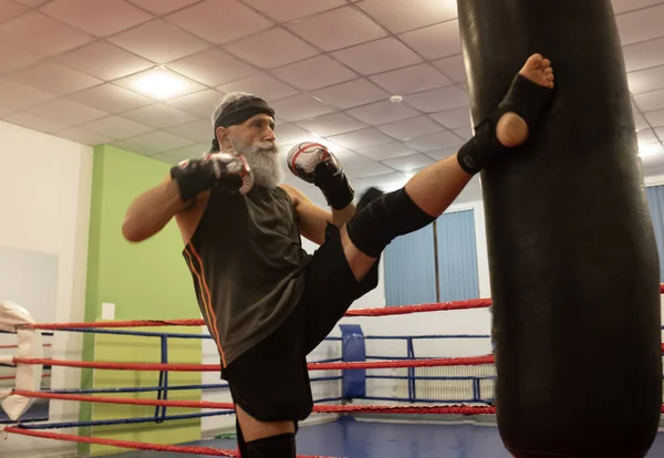 Senior male boxer ready to fight. Senior boxer in gloves boxing in gym