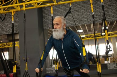 Spor salonunda trx dirençli bantlarla kıdemli sporcu eğitimi almış..