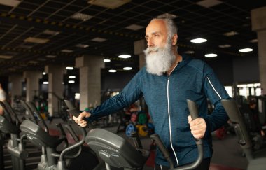 Spor salonundaki koşu makinesindeki son sınıf sakallı adam. Koşu bandı. 