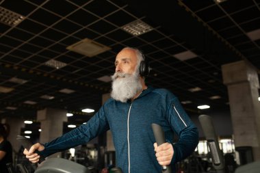Spor salonundaki koşu makinesindeki son sınıf sakallı adam. Koşu bandı. 