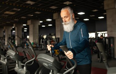 Spor salonundaki koşu makinesindeki son sınıf sakallı adam. Koşu bandı. 