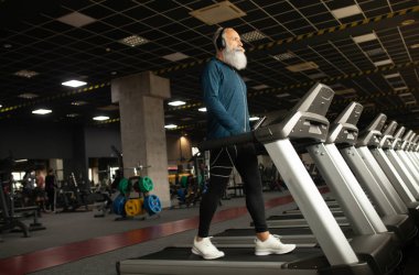 Spor salonundaki koşu makinesindeki son sınıf sakallı adam. Koşu bandı. 