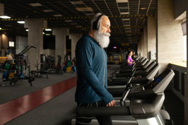 Spor salonundaki koşu makinesindeki son sınıf sakallı adam. Koşu bandı. 