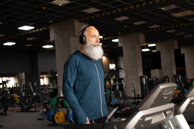 Spor salonundaki koşu makinesindeki son sınıf sakallı adam. Koşu bandı. 