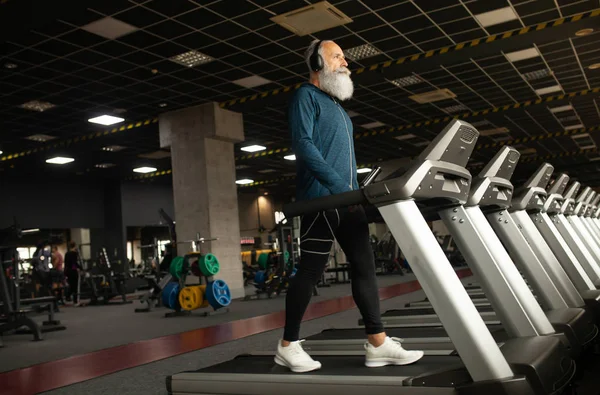 Spor salonundaki koşu makinesindeki son sınıf sakallı adam. Koşu bandı. 