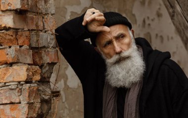 Siyah giysiler giyen yaşlı sakallı bir adam. Dışarıdaki Erkekler portresi.