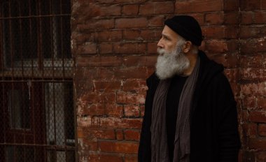 Siyah giysiler giyen yaşlı sakallı bir adam. Dışarıdaki Erkekler portresi.