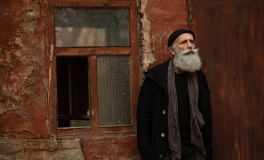 Siyah giysiler giyen yaşlı sakallı bir adam. Dışarıdaki Erkekler portresi.