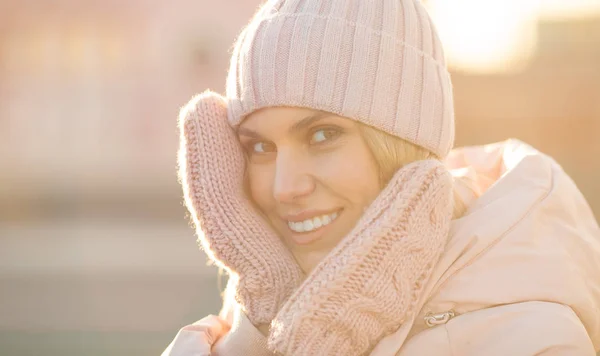 Portrait of a beautiful young model in pink knitted hat  and mittens. Beautiful natural young smiling blonde woman wearing knitted gloves.