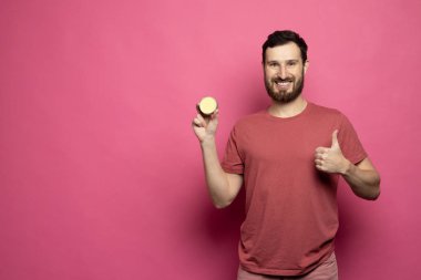 Close-up image of handsome bearded man holding beard balm on pink background.