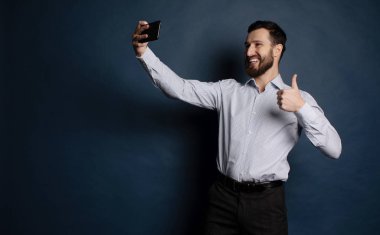 Business man taking selfie from phone on blue background
