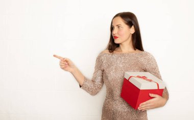 Smiling young beautiful woman holds red gift box. Isolated over white background. 