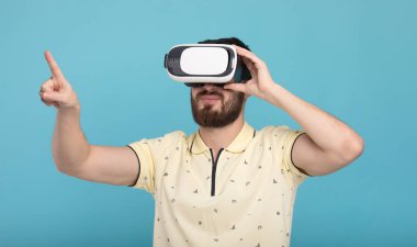 Genç adam dokunmaya çalışıyorum Vr gözlük kulaklık kullanarak sanal gerçeklik nesneleri. İzole beyaz arka plan.