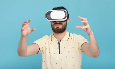 Genç adam dokunmaya çalışıyorum Vr gözlük kulaklık kullanarak sanal gerçeklik nesneleri. İzole beyaz arka plan.