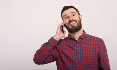 Beyaz arka planda akıllı telefonunu kullanan yakışıklı, sakallı bir adam.