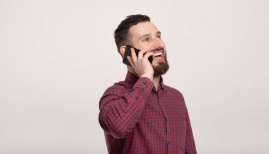 Beyaz arka planda akıllı telefonunu kullanan yakışıklı, sakallı bir adam.