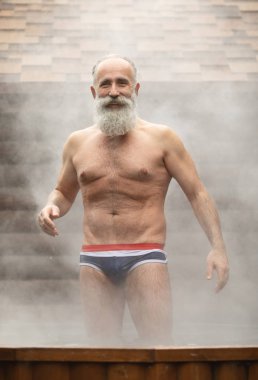 Bearded senior man enjoying thermal bath in thalassotherapy center. clipart