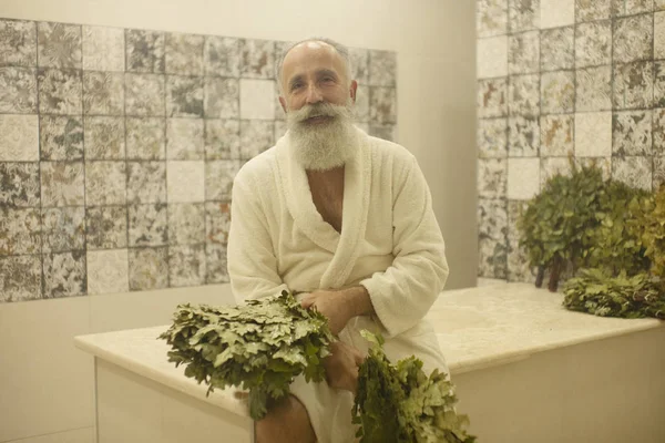 Bearded senior Man is taking a steam-bath in sauna. Russian bath.