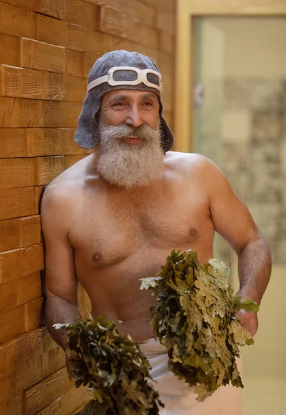 Bearded senior Man is taking a steam-bath in sauna. Russian bath.