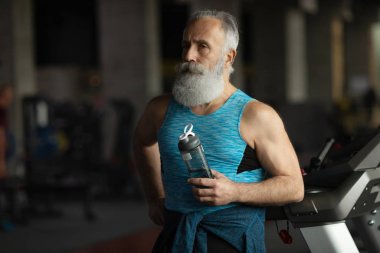 Spor salonundaki yaşlı sakallı adam. Egzersiz sonrası dinlenme