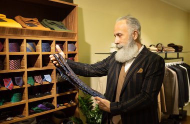 Şık ve modern kıdemli iş adamı pahalı mağazalarda kravat seçip alıyor..