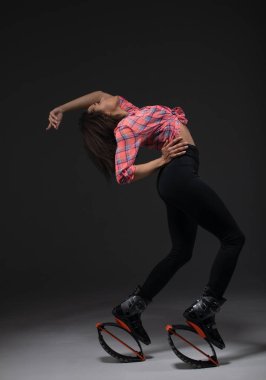 Young and pretty fitness instructor makes exercise using jumping boots.
