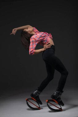 Young and pretty fitness instructor makes exercise using jumping boots.