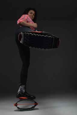 Young and pretty fitness instructor makes exercise using jumping boots.