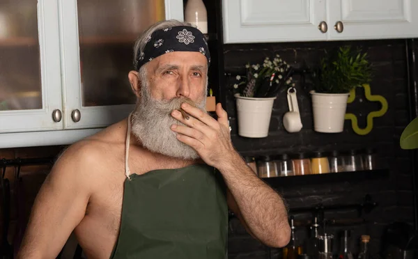 Bearded senior man smoking marijuana (weed, cannabis) at home.