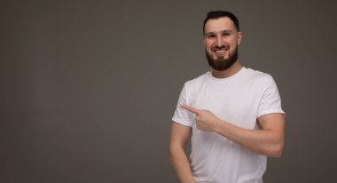 Sakallı, günlük kıyafetleri olan ve kameraya gülümseyen genç yakışıklı bir adam..