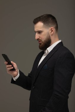 Akıllı telefondan mesaj gönderen genç adam gri arka planda izole edilmiş..