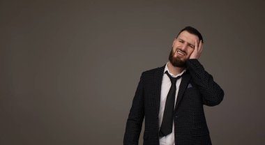 Genç adam şiddetli baş ağrısı, acı gri arka plan üzerinde izole gözleri çaresiz yüz ifadesi ile ağrı gidermek için kapanış tapınaklar, parmak basarak portresi