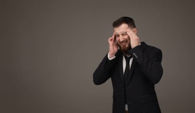 Genç adam şiddetli baş ağrısı, acı gri arka plan üzerinde izole gözleri çaresiz yüz ifadesi ile ağrı gidermek için kapanış tapınaklar, parmak basarak portresi