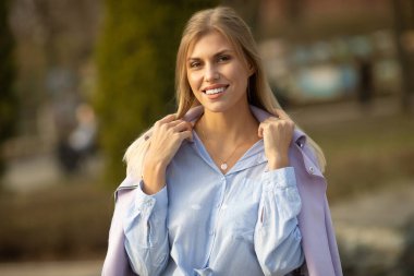 Çekici, genç, sarışın kadın portresi. Baharın güneşli arka planında bir kadın. Sonbaharda neşeli bir kadın portresi..