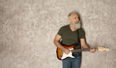 Sakallı yaşlı adam gitar çalıyor.