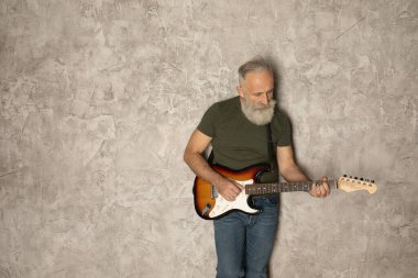 Sakallı yaşlı adam gitar çalıyor.