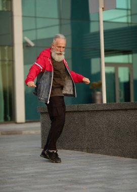 Şehirde yürüyen aktif kıdemli bir adam. Dışarıda dikilen sakallı yaşlı bir adamın portresi..