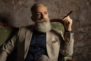 Karanlık bir odada elinde puroyla çekici sakallı bir iş adamının portresi..