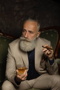 Bir bardak viski taşıyan şık, yakışıklı, sakallı adam..