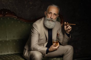 Bir bardak viski taşıyan şık, yakışıklı, sakallı adam..