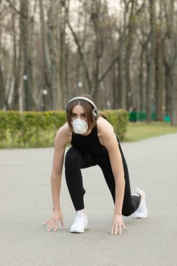 Parkta koşarken tıbbi koruma maskesi takan beyaz kadın portresi. Corona virüsü ya da Covid-19 tüm dünyaya yayılıyor..