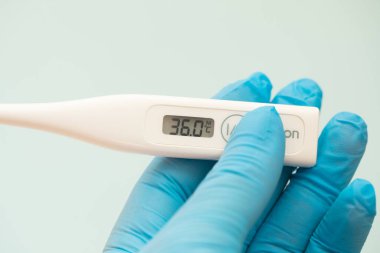 Eldivenli bir kız elinde termometre tutuyor. Sağlık hizmetleri kavramı.