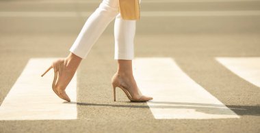 Yaya geçidinde yürüyen kadın bacaklarına yakın dur. Kadın yüksek topuklu ayakkabı giyiyor..