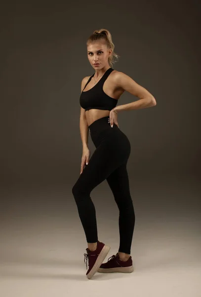 Gelukkige Jonge Vrouw Sportkleding Glimlachend Musculair Fitnessmodel Grijze Achtergrond Kijkend — Stockfoto