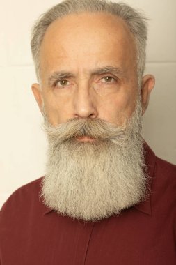 Mükemmel sakal. Gri arka planda duran yaşlı sakallı adamın yakın çekimi..