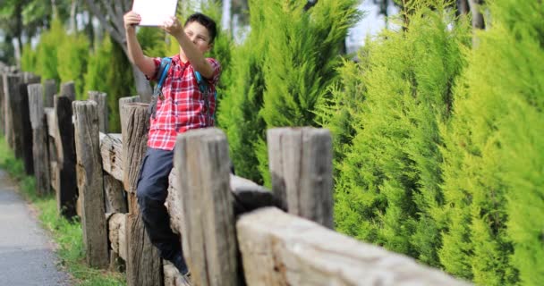 Sonriente jovencito haciendo foto selfie en el verde parque de primavera — Vídeo de stock